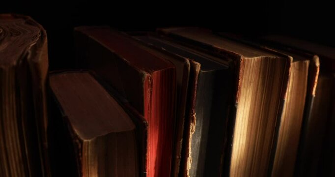 Stack of old antique books in a ray of light. Close-up view, slider macro 4K video.