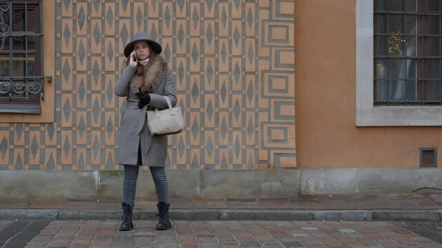A worried woman stands on a city street, having a serious personal phone call. A concept of receiving bad news, relationship problems, or dealing with a difficult issue.