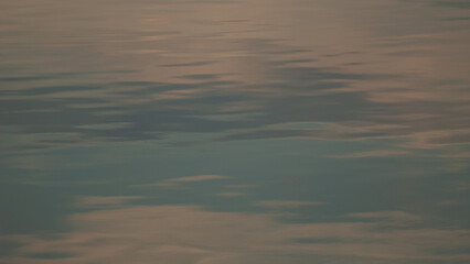 Reflection of the sky on the surface of the water of a mountain lake early in the morning.