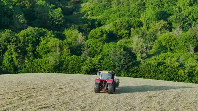 Farmer harvests hay with a tractor in the fields of Devon, Torquay, England