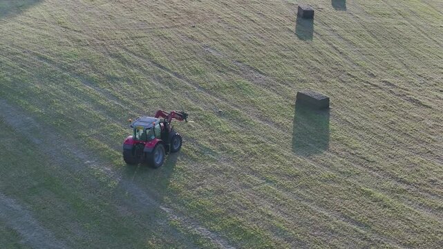Farmer harvests hay with a tractor in the fields of Devon, Torquay, England