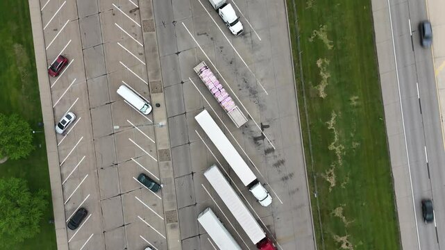 Top-down view of a truck parking area near highway. Rows of parked lorries and 