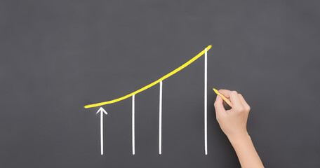 Hand drawing upward trending graph on chalkboard