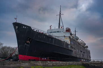 Dramatic low-angle shot of the TSS Duke of Lancaster, a beached and weathered ship with a black...