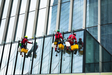 Professional window cleaners working on a glass skyscraper in full safety gear. High-risk job, urban landscape, safety protocols