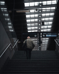 old man walking up stairs at train station