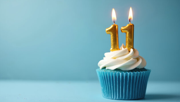 Gold candle numbers eleven in cupcake with white icing on blue background. Dessert for 11 years old birthday party. Cupcake, candle, celebration, happy birthday.