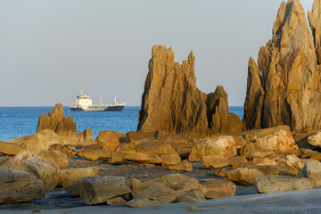 夕陽に照らされる橋杭岩と遠くに浮かぶ船