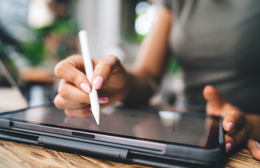 Macro view of woman using stylus on tablet screen, editing or analyzing investment data, crypto...