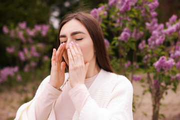 Obraz na płótnie Canvas Woman suffering from seasonal pollen allergy near blossoming shrub on spring day