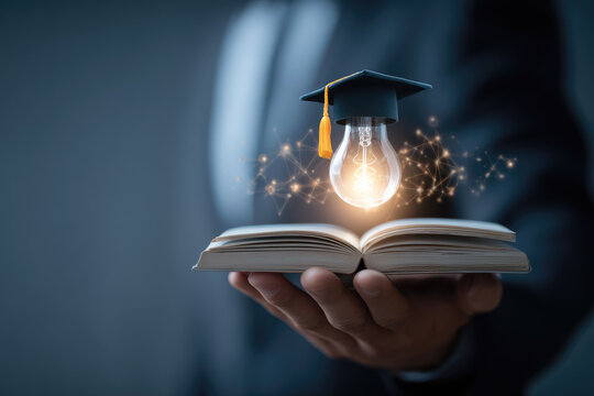 Concept of online education course or distance learning using wireless internet technology, businessman hand holding light bulb with book showing learning new things with graduation cap on virtual - Powered by Adobe