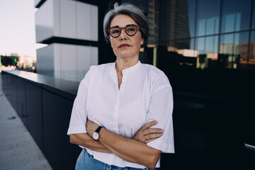 Focused female professional standing with arms crossed, projecting strength and confidence. Symbol...