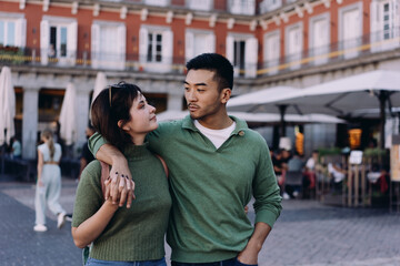 Multicultural couple gazing at each other in public square, reflecting intimacy, trust, and...