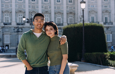 Happy travelers posing for photo near landmark in Madrid, wrapped in warm light and joyful...