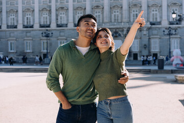 Tourist couple enjoying bright morning in front of palace, pointing at distant view with joy and...