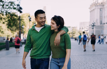 Couple walking arm in arm, deeply gazing into each other’s eyes while smiling. Urban setting,...
