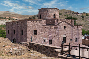 The historic Aya Eleni Church, or St. Helena Church in Sille, Konya, Turkey. Ancient stone building in a mountain landscape under a blue sky on a sunny day