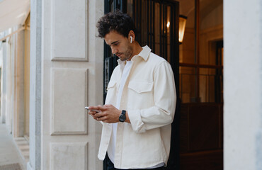 Hispanic Man checking notifications on smartphone, responding to emails, or participating in...