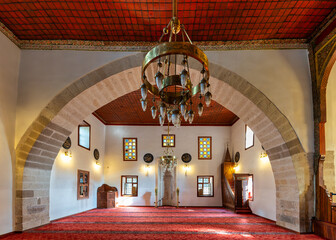 Inside Shems-i Tebrizi Mosque and Tomb, the exquisite architecture showcases detailed arches and stained glass windows. Visitors admire the serene atmosphere during a quiet afternoon