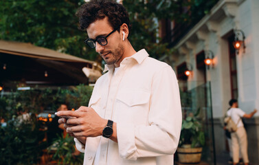 young entrepreneur checking his phone outdoors. Male confident and focused expression suggests he...