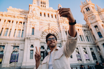 digital male nomad enthusiastically takes a selfie in front of an iconic architectural masterpiece....