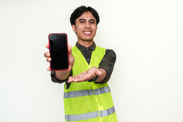 Happy Asian construction worker showing blank smartphone screen to the camera with cheerful...