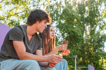 Fototapeta premium Teenage girl in love with a boy eating ice cream and laughing outdoors. Couple Dating Love Theme Park Concept