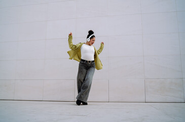 Joyful young woman dances energetically in contemporary cityscape, embracing rhythm movement....