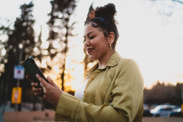 Smiling young woman looking at her tablet in the golden hour, enjoying online interaction. soft...