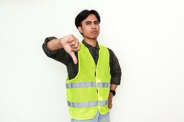 Portrait of a serious Asian construction worker showing thumbs down gesture, isolated on white...