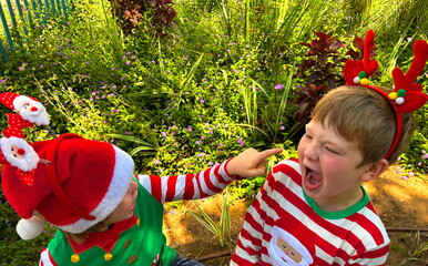 Preschool boys in Christmas costumes near palm tree. Children laugh while relaxing at resort on...