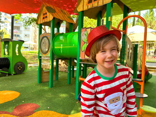 Little preschool boy in Santa Claus costume on playground, in kindergarten at resort. Christmas in...