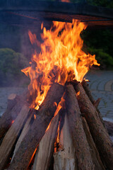 Pile of wood is burning and the flames are orange. The fire is in the middle of a pile of wood.