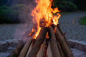 Pile of wood is burning and the flames are orange. The fire is in the middle of a pile of wood.