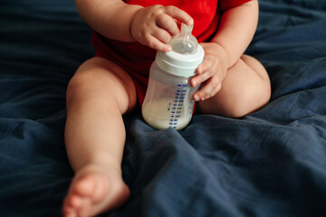 Cute sweet baby holding bottle with milk, healthy baby food concept, cozy lifestyle