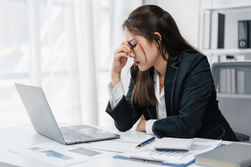 Stressed Asian Businesswoman Feeling Anxious at Work with Headache and Burnout. Depressed Office Worker Experiencing Mental Health Problem Due to Overwork and Financial Crisis