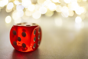 Image of a glossy six-sided die against a blurred, celebratory background, symbolizing success or...