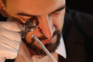Appraiser with loupe evaluating luxury gemstone indoors, closeup