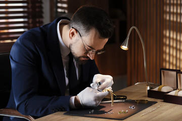 Appraiser with loupe evaluating luxury wristwatch at table indoors