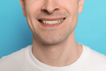 Smiling man after shaving on light blue background, closeup