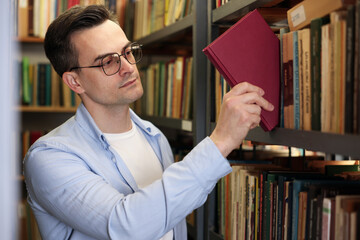 Man taking book from shelf in public library