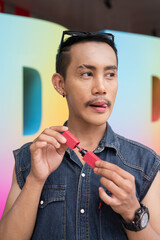 Portrait of confident non binary gay man holding lipstick
