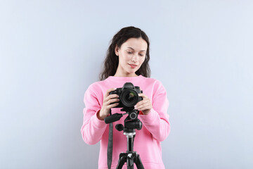 Woman with professional video camera on light grey background