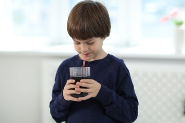 Cute little boy drinking refreshing soda at home