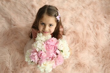 Cute little girl with bouquet of beautiful peonies on faux fur indoors, above view. Space for text