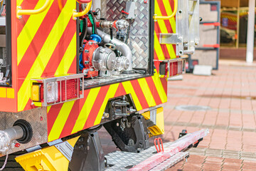 Image of a yellow and red fire truck on a brick roadway, equipped with reflective markings and a large pump