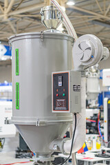 Large industrial mixerprocessor with cylindrical base and two silver tanks, indoors in an industrial setting, artificial lighting, no people, metallic hues, blue components, functional style, side v