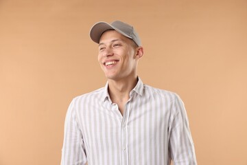 Young man in stylish baseball hat on beige background