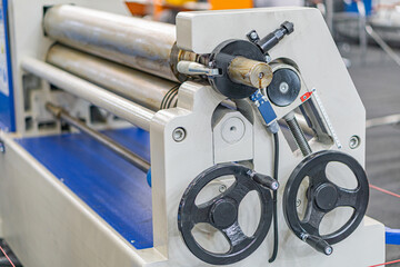 Close-up of a mechanical assembly line cylinder with knobs in an industrial setting, surrounded by other machinery