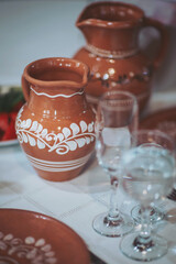 Ceramic pitchers and elegant glassware decorate a rustic dining table filled with fresh produce, reflecting a warm, inviting atmosphere for a heartfelt gathering
